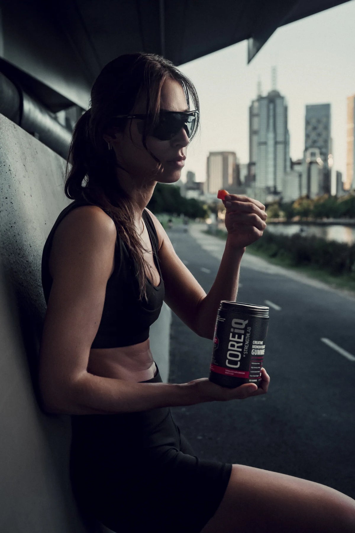 Woman eating a CoreIQ creatine gummy, Melbourne skyline behind