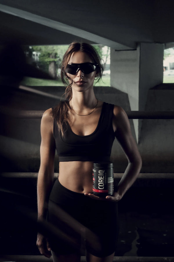 Woman holding a CoreIQ Creatine Gummies jar under a bridge