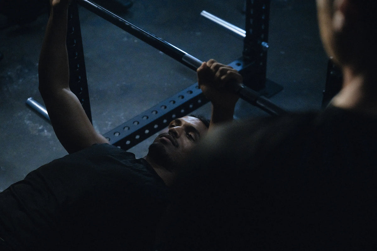 Bench press with a spotter, seen over the spotter's shoulder