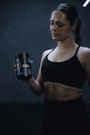 Woman holding a CoreIQ Magnesium Gummies jar