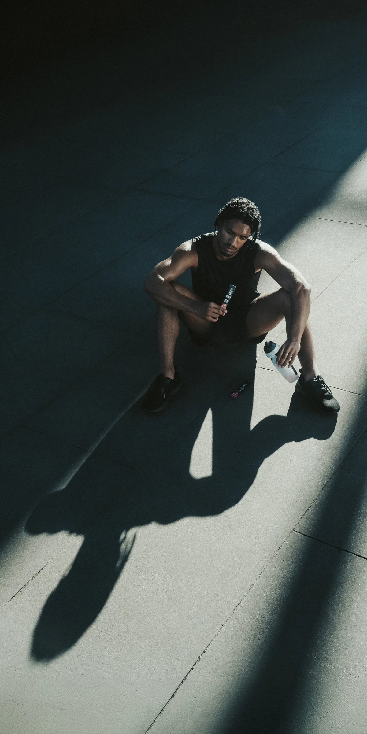 Athlete resting on a gym floor in shafts of light