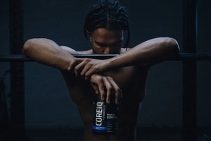 Athlete resting on a barbell, holding a CoreIQ Magnesium Gummies jar