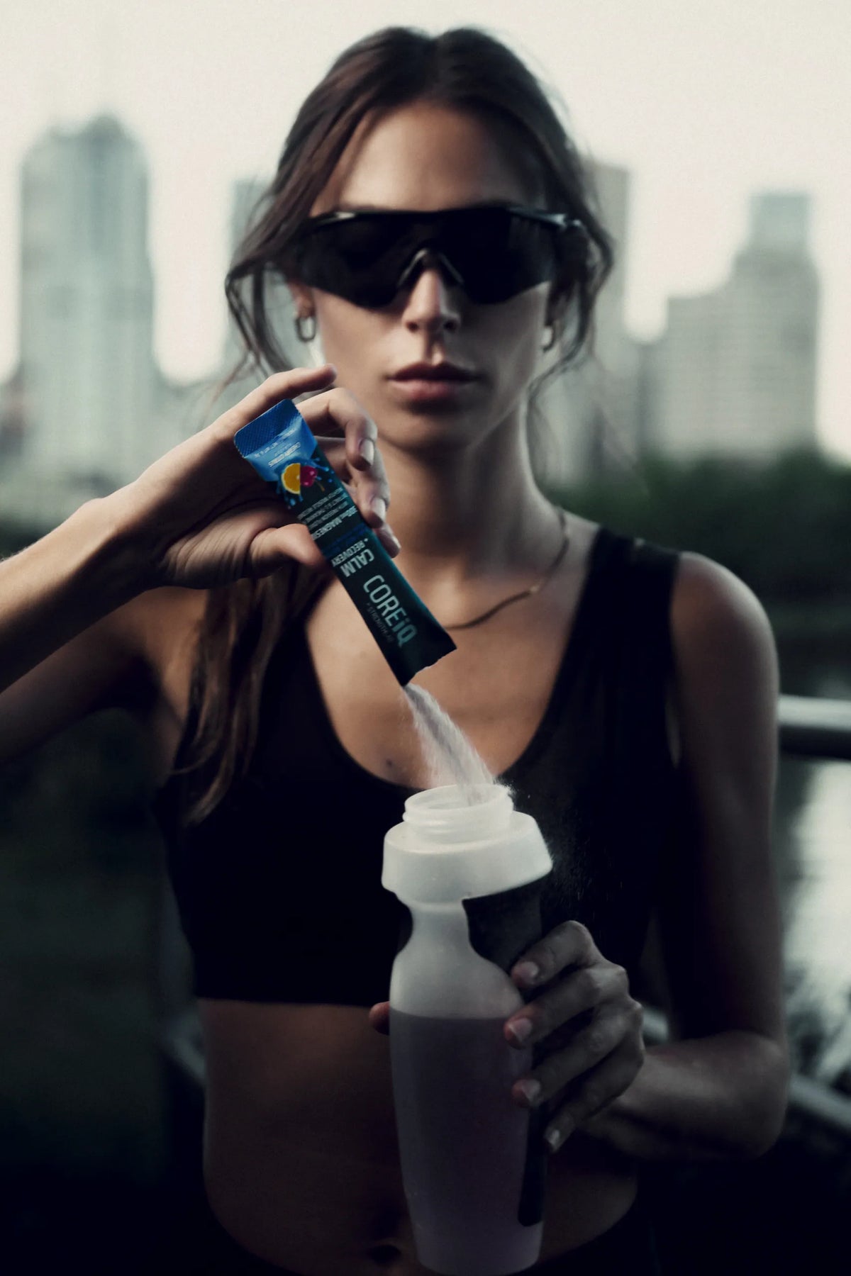 Woman pouring a CoreIQ sachet into a water bottle